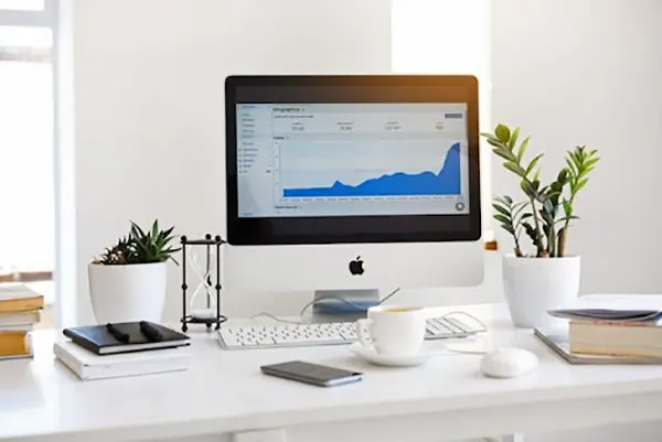 A computer screen with a rising graph on a white table